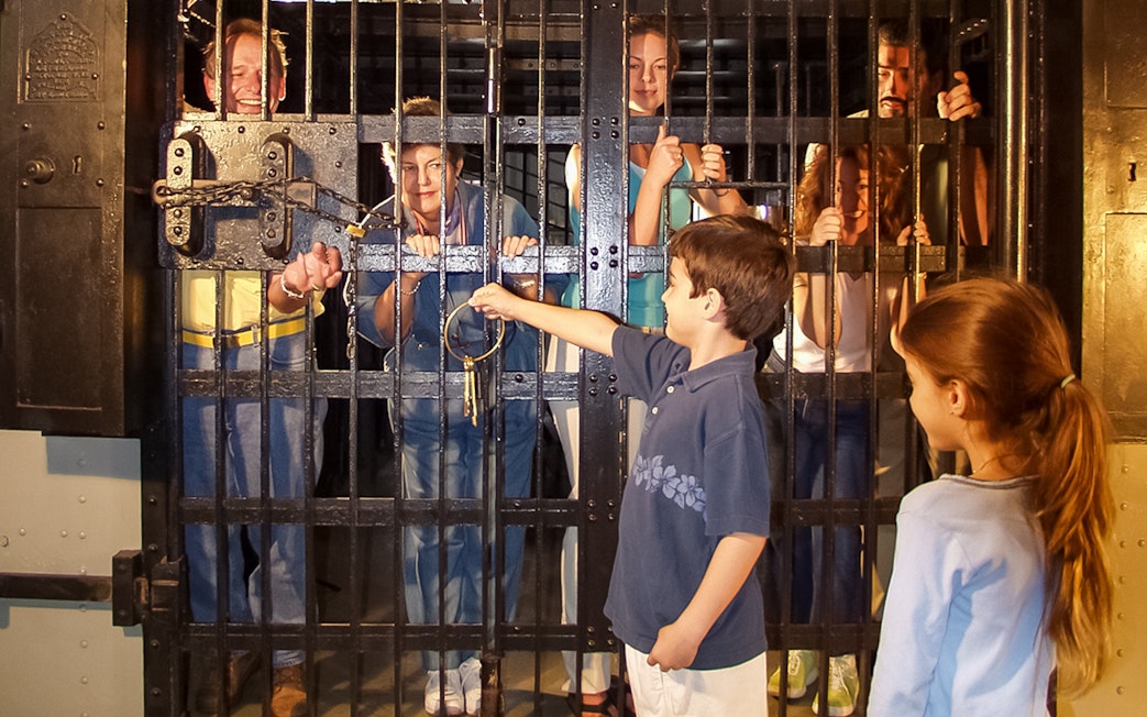 Visitors inside a cell at St. Augustine Old Jail Museum, with a child holding keys.