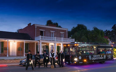 Ghost tour trolley in St. Augustine with guides holding lanterns at night.