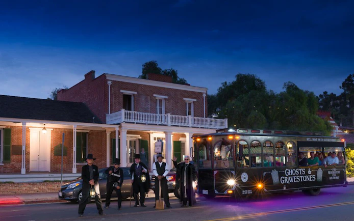 Ghost tour trolley in St. Augustine with guides holding lanterns at night.
