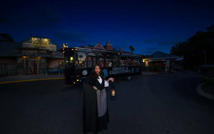 St. Augustine Ghosts & Gravestones tour guide with lantern near trolley at night.