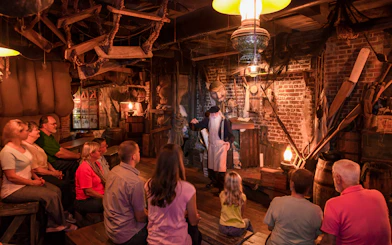 Tour guide narrating ghost stories to visitors in a dimly lit room, St. Augustine.