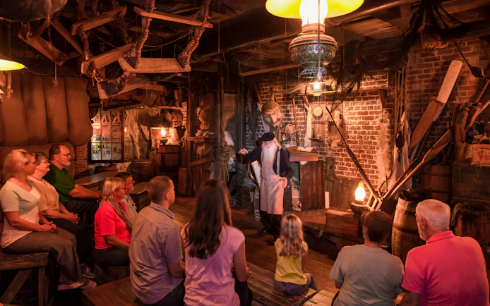 Tour guide narrating ghost stories to visitors in a dimly lit room, St. Augustine.