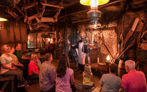 Tour guide narrating ghost stories to visitors in a dimly lit room, St. Augustine.