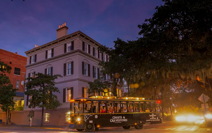 St. Augustine Ghosts & Gravestones tour trolley at dusk near historic building.