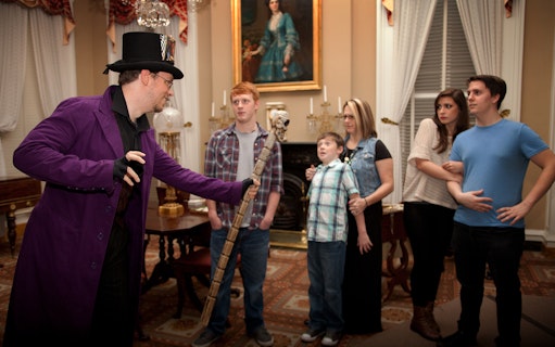 Guide in costume leading a group on St. Augustine Ghosts & Gravestones tour indoors.