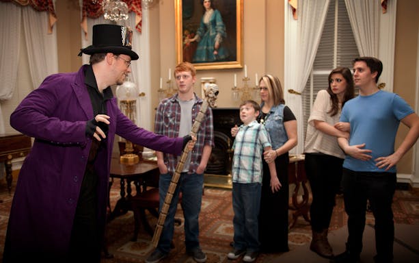 Guide in costume leading a group on St. Augustine Ghosts & Gravestones tour indoors.