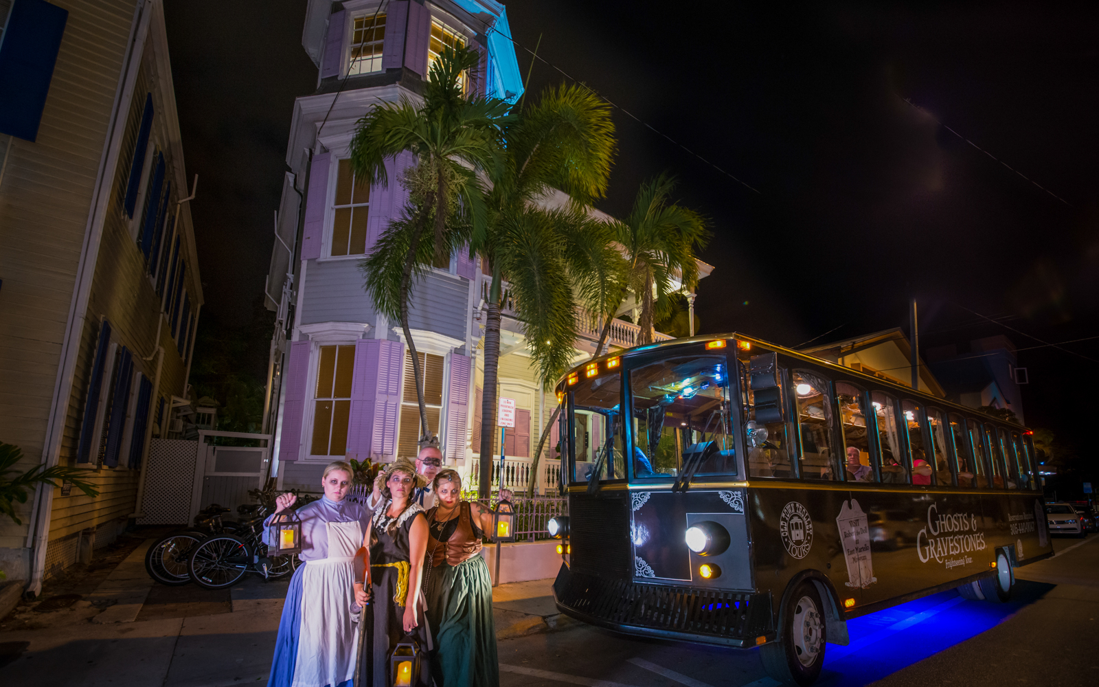 St. Augustine Ghosts & Gravestones tour trolley at night with costumed guides holding lanterns.