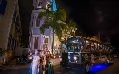 St. Augustine Ghosts & Gravestones tour trolley at night with costumed guides holding lanterns.