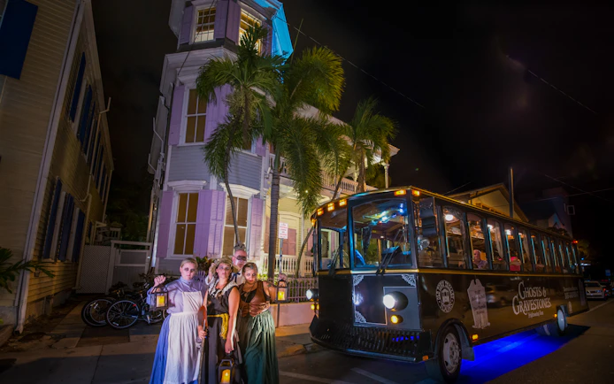 St. Augustine Ghosts & Gravestones tour trolley at night with costumed guides holding lanterns.
