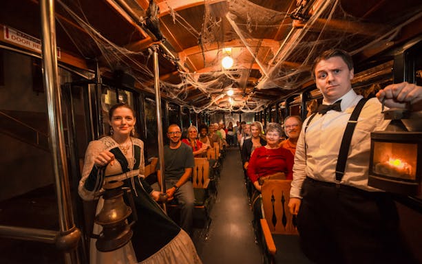 St. Augustine ghost tour participants on a trolley with guides holding lanterns.