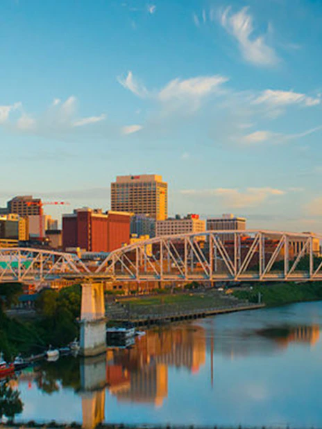 Nashville skyline with bridge over Cumberland River at sunset.