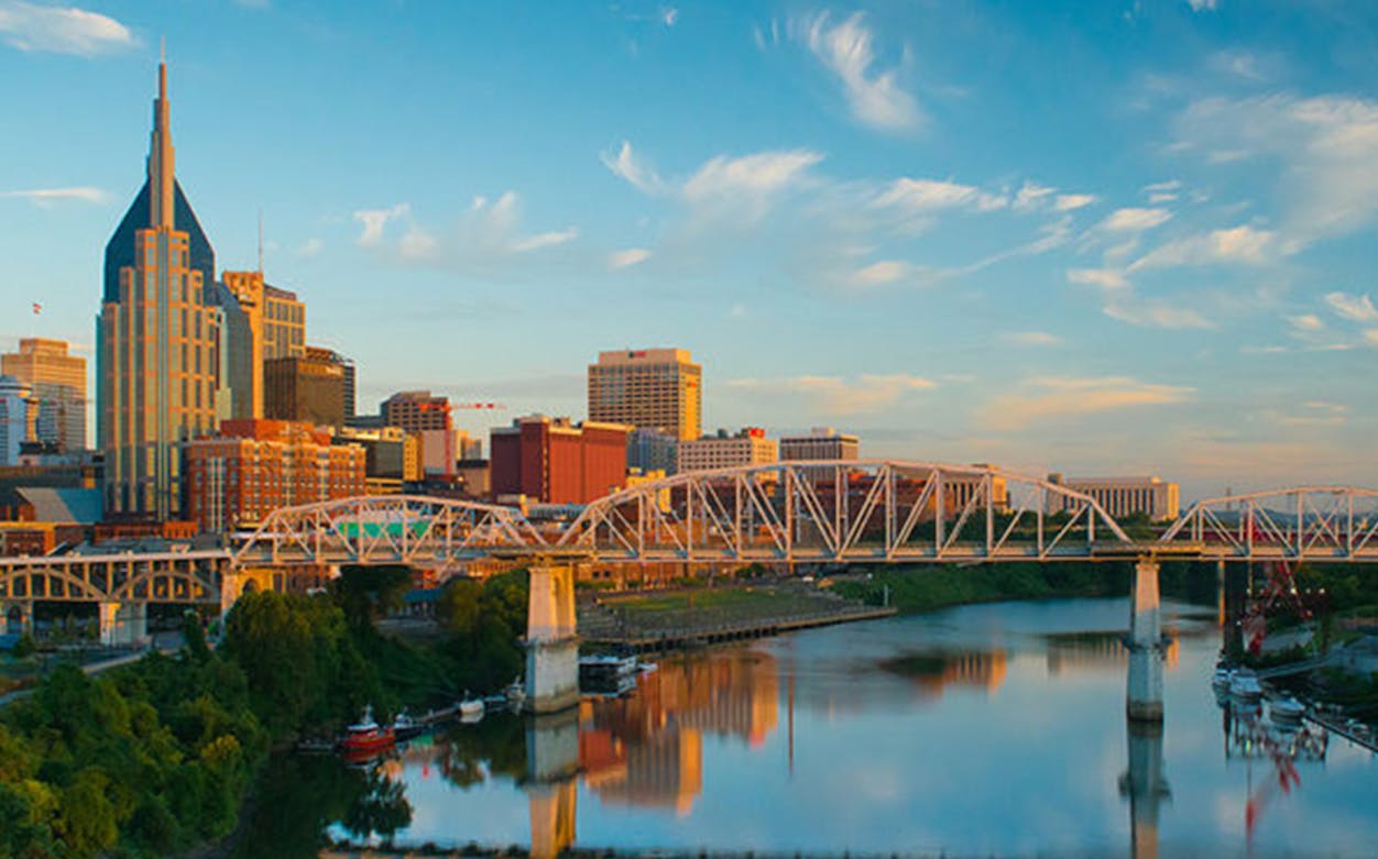 Nashville skyline with bridge over Cumberland River at sunset.