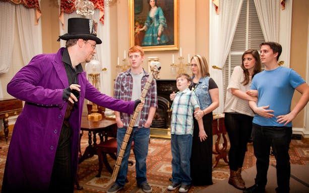Guide in costume leading a group on the Boston Ghosts & Gravestones tour indoors.