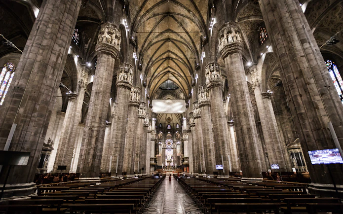 Interior view of Milan Duomo with towering columns and ornate ceiling.