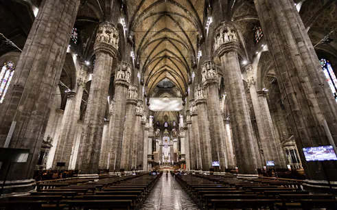 Interior view of Milan Duomo with towering columns and ornate ceiling.