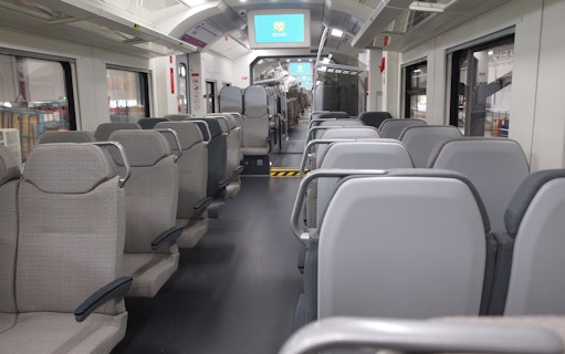 Interior of KLIA Ekspres train with empty seats and digital screens.