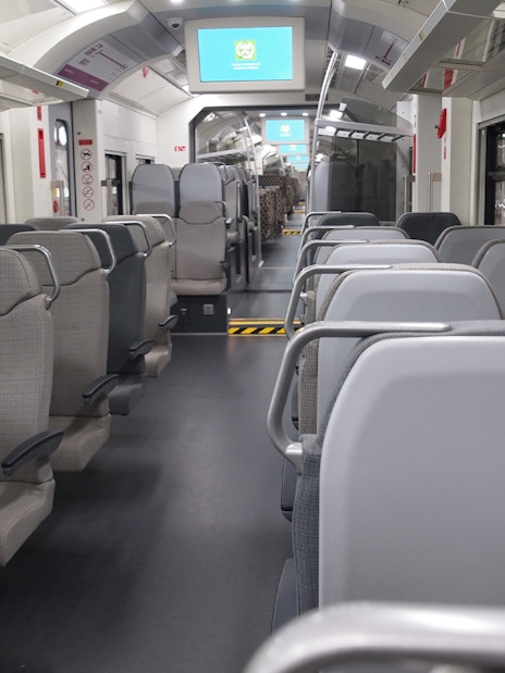 Interior of KLIA Ekspres train with empty seats and digital screens.