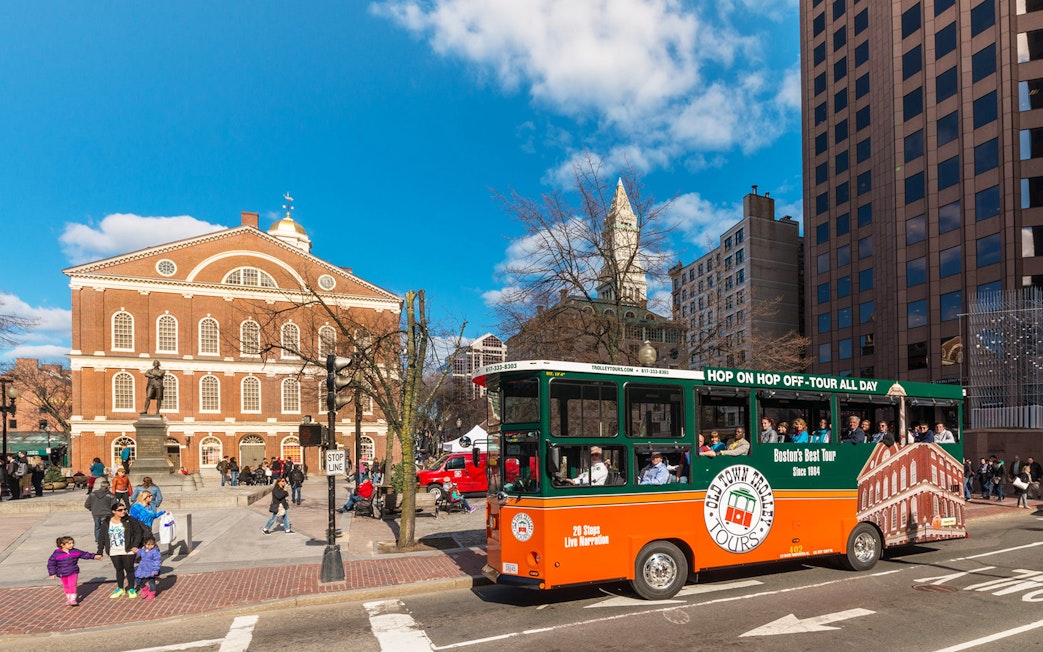 Boston Old Town Trolley passing Faneuil Hall with tourists onboard.