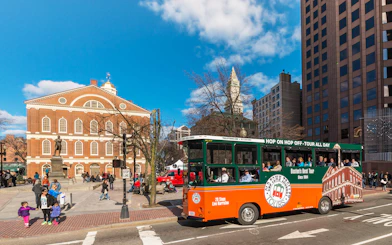 Boston Old Town Trolley passing Faneuil Hall with tourists onboard.