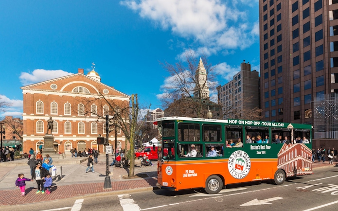 Boston Old Town Trolley passing Faneuil Hall with tourists onboard.