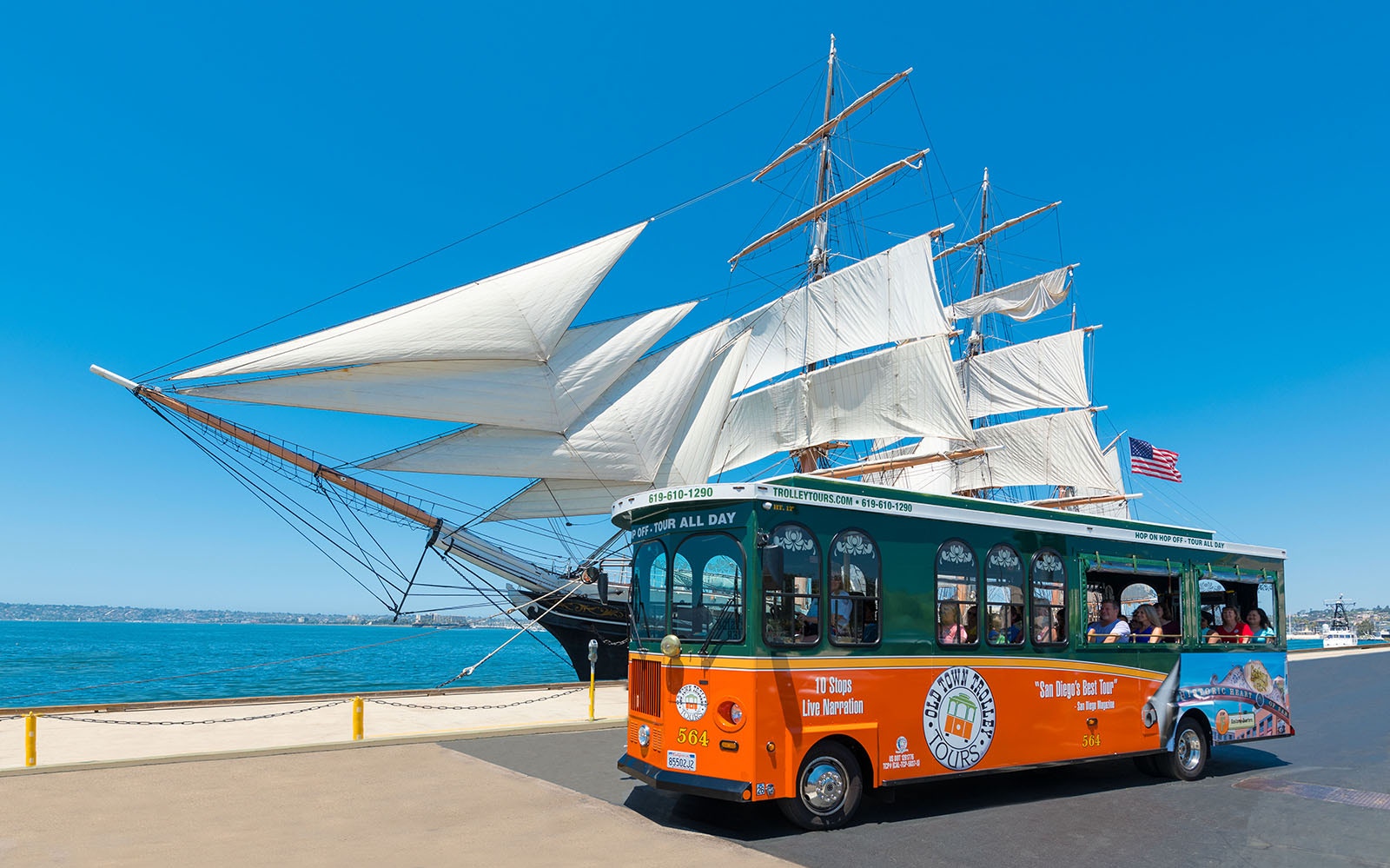 San Diego Old Town Trolley passing a historic sailing ship by the waterfront.
