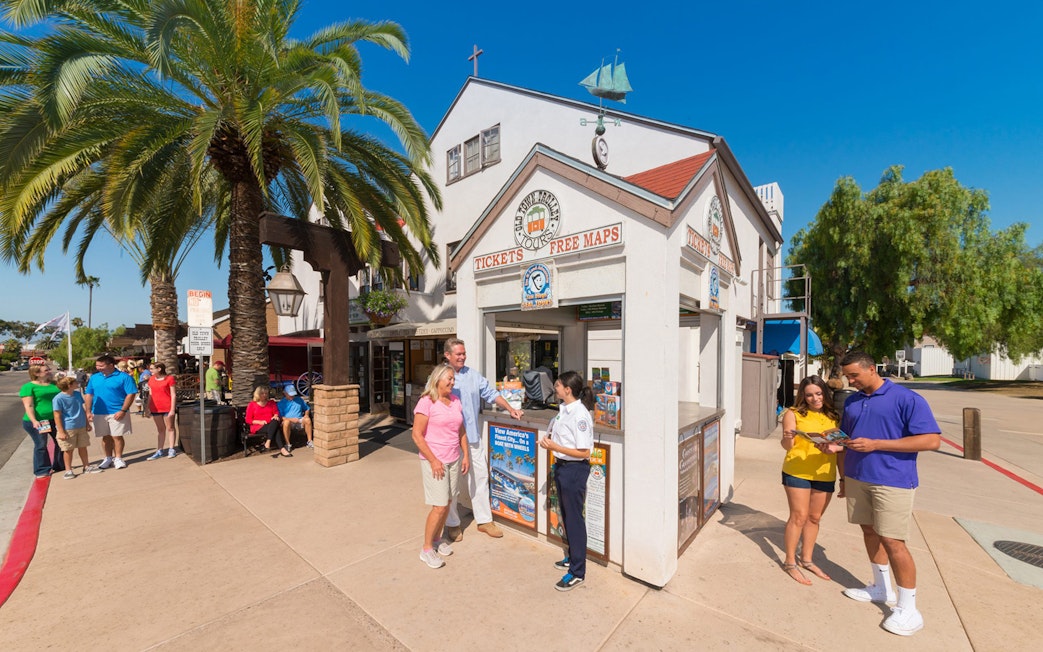 Ticket booth for Old Town Trolley Tour with people receiving maps and information.
