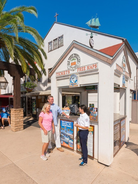 Ticket booth for Old Town Trolley Tour with people receiving maps and information.
