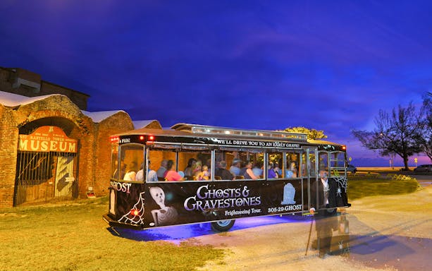 Guided trolley tour at night near Savannah museum entrance.