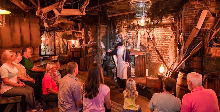 Group listening to a storyteller in a dimly lit room on the Savannah Ghosts & Gravestones tour.