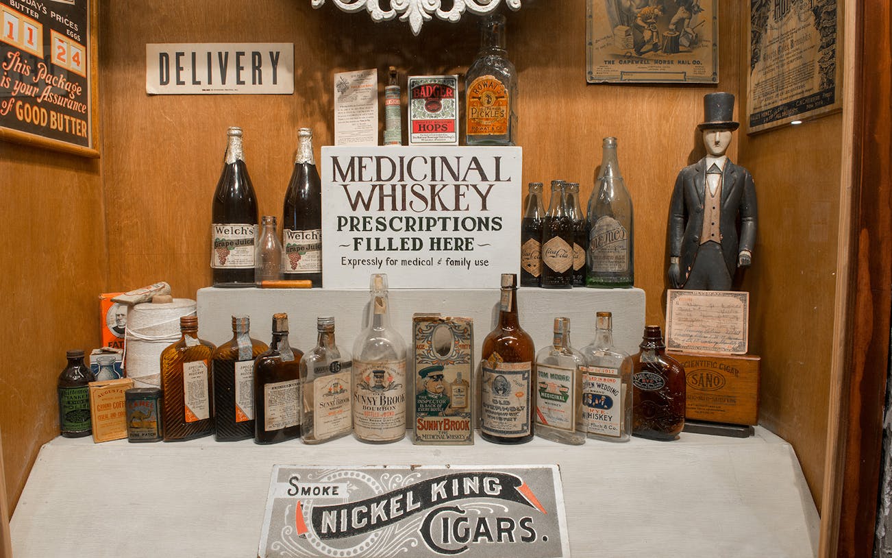 Medicinal whiskey display at American Prohibition Museum with vintage bottles and signage.
