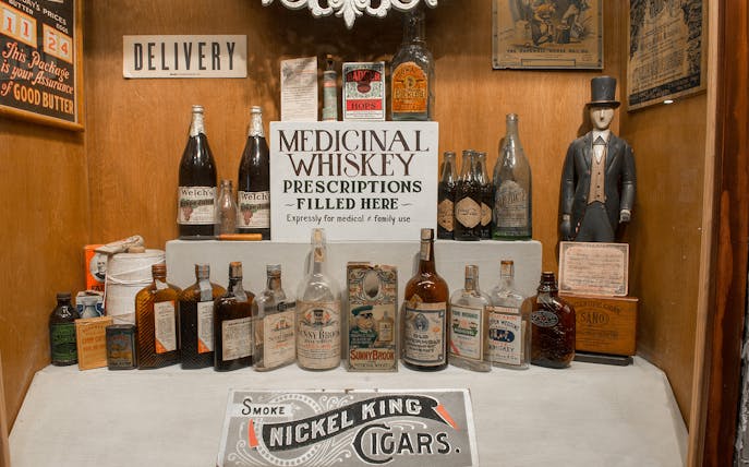 Medicinal whiskey display at American Prohibition Museum with vintage bottles and signage.