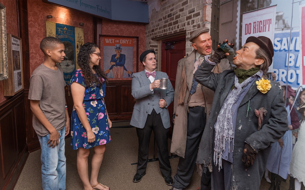 Visitors observing Prohibition-era figures at the American Prohibition Museum exhibit.