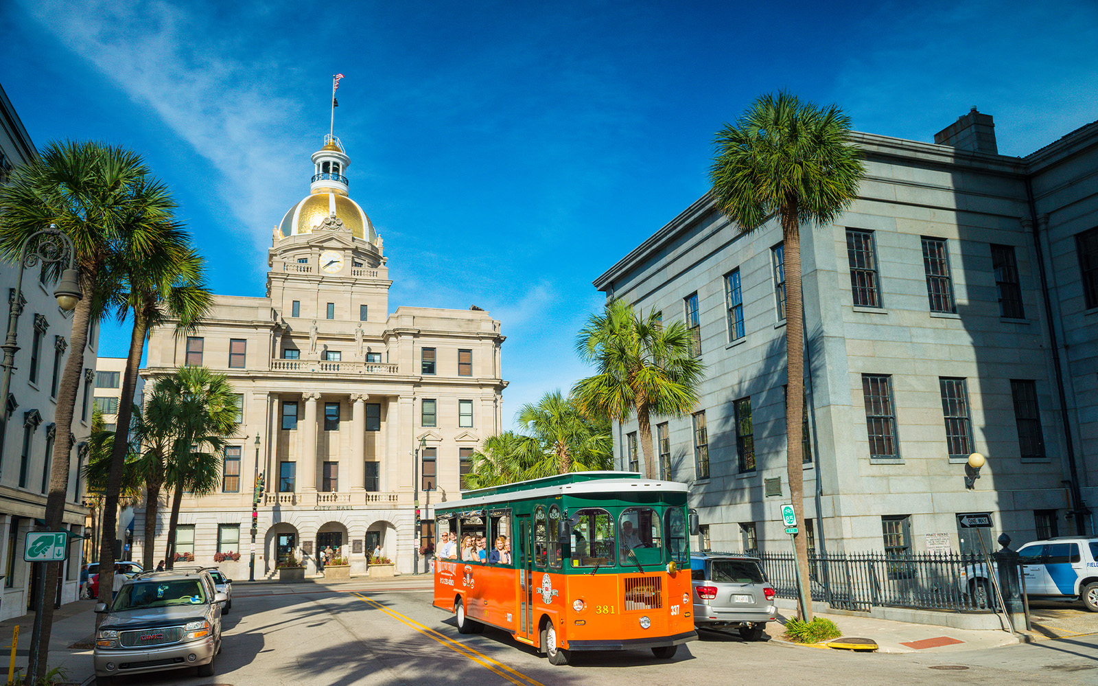 Savannah trolley passing City Hall with golden dome on sightseeing tour.