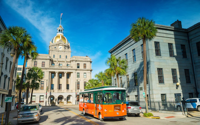 Savannah trolley passing City Hall with golden dome on sightseeing tour.