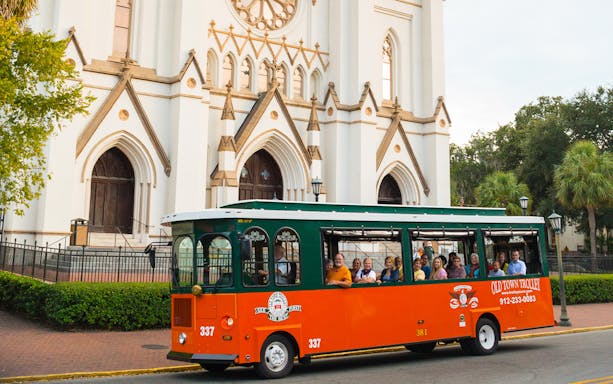 Trolley tour in front of historic cathedral in Savannah's Old Town.