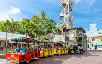 Guided Conch Tour Train with passengers in Key West near historic building.
