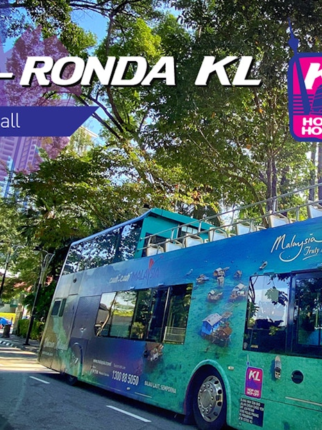 Kuala Lumpur hop-on hop-off bus on a tree-lined street, promoting city sightseeing.