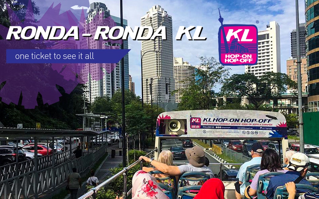 Kuala Lumpur Hop On Hop Off bus with city skyline in the background.