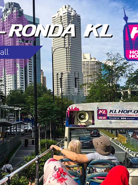 Kuala Lumpur Hop On Hop Off bus with city skyline in the background.