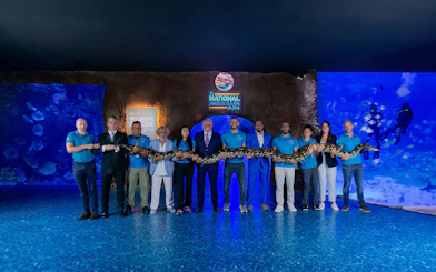 Group holding a large snake at National Aquarium Abu Dhabi's Beyond The Glass Experience.