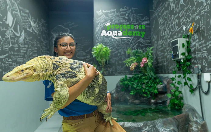 Person holding a large lizard at National Aquarium Abu Dhabi's Bu Tinah Dhow Experience.
