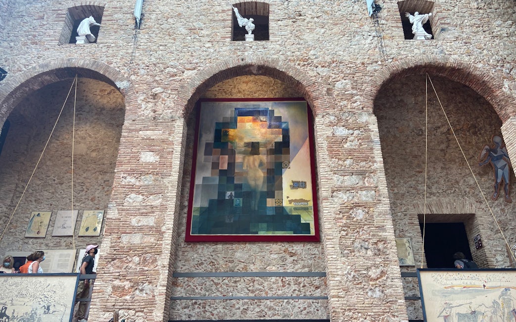 Dalí Museum tour with visitors viewing a large surrealist painting on a brick wall.