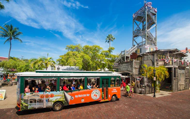 Key West Old Town Trolley in front of Shipwreck Museum with tourists onboard.