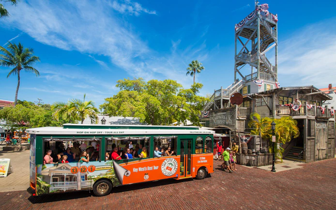 Key West Old Town Trolley in front of Shipwreck Museum with tourists onboard.