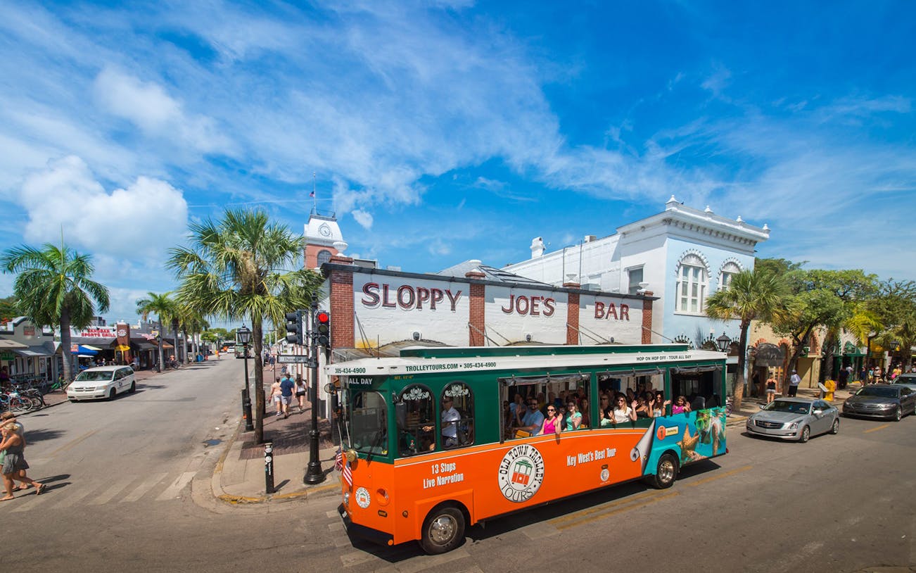 Key West Old Town Trolley passing Sloppy Joe's Bar on a sunny day.
