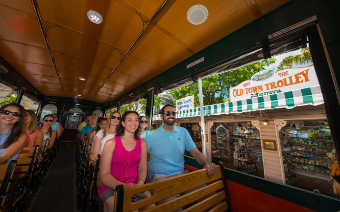 Passengers enjoying the Key West Old Town Trolley tour near local shops.