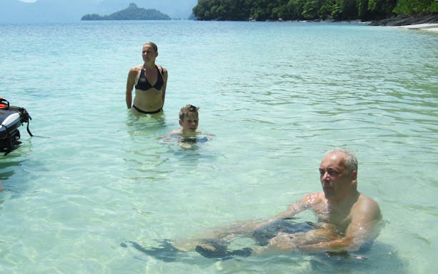 People enjoying the clear waters of Intan Kecil Island, Langkawi, near a banana boat.