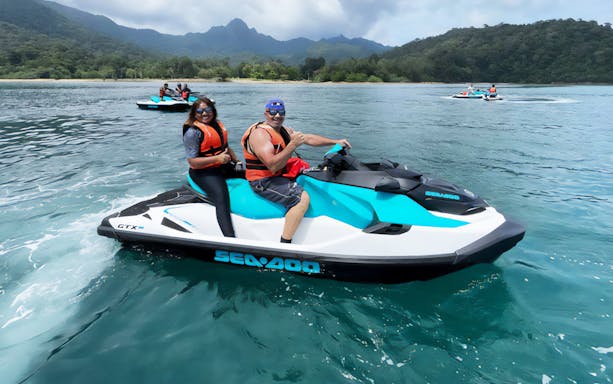 Jet ski riders enjoying Langkawi Makan Makan Food Tour on turquoise waters with lush hills in the background.