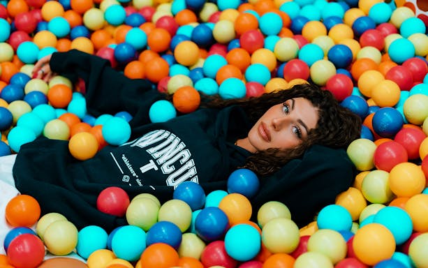 Person relaxing in a colorful ball pit at Selfie Museum Firenze.