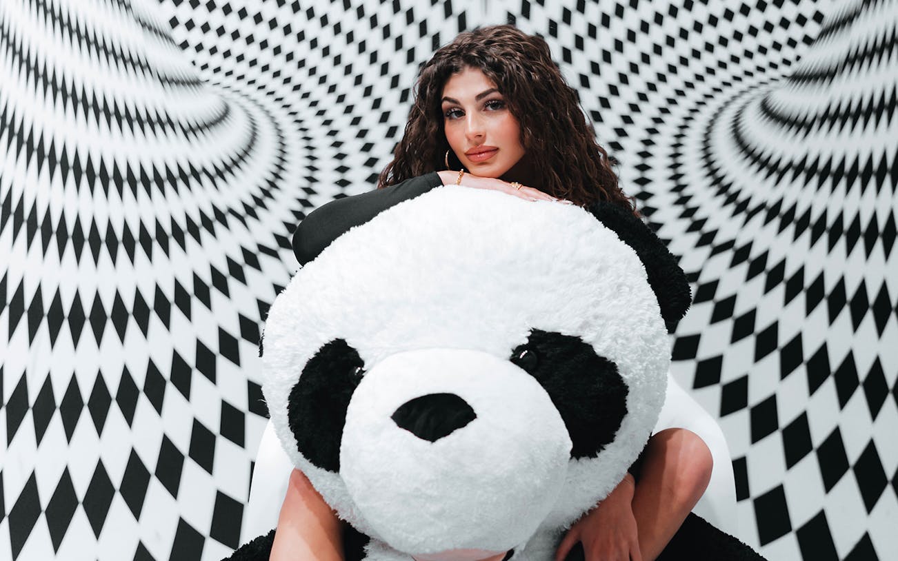 Person with large panda plush in optical illusion room at Selfie Museum Firenze.
